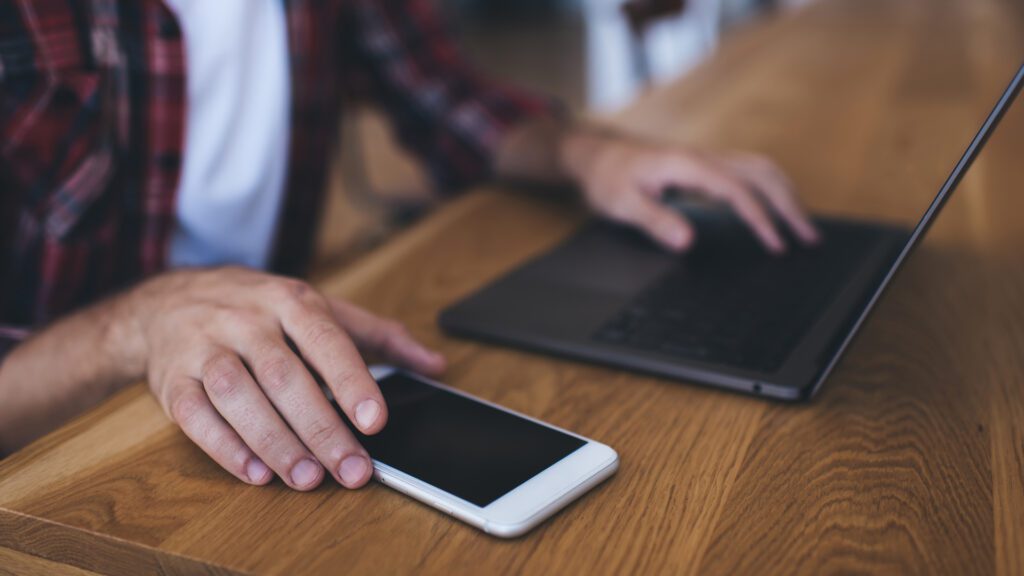 A man with both a phone and computer used to search
