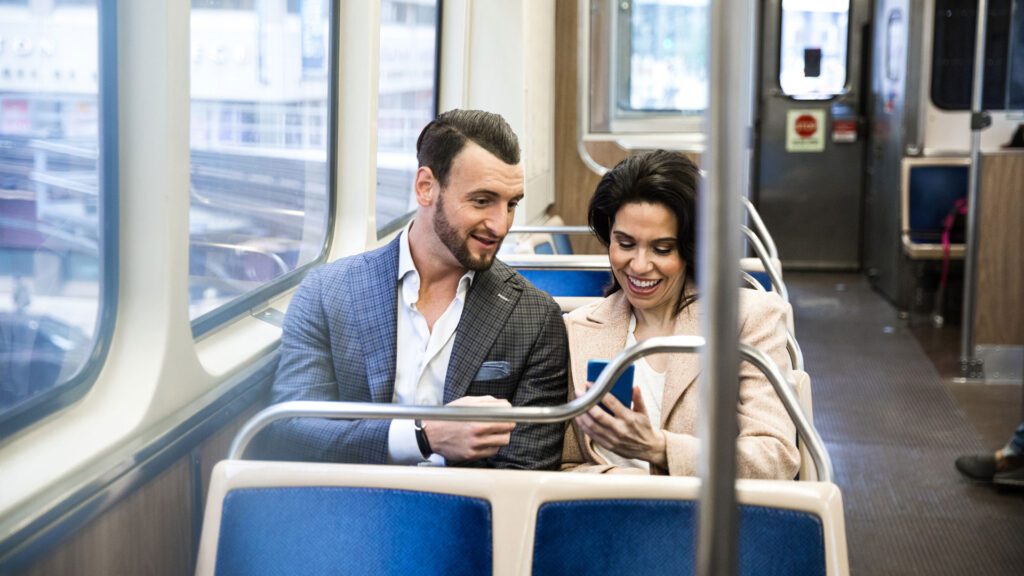 People on a train looking at a phone with digital marketing.